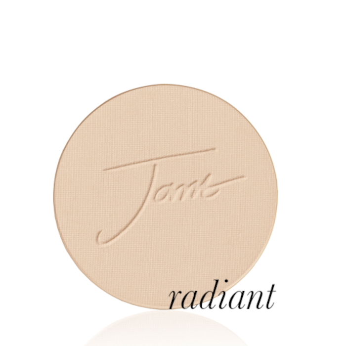 Okrągły, prasowany puder do twarzy marki Jane Iredale w odcieniu Radiant: jasny beż z subtelnie brzoskwiniowym, ciepłym podtonem z wytłoczonym logo Jane Iredale.