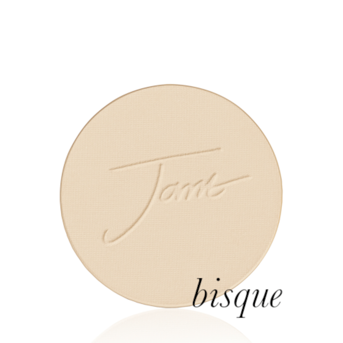 Okrągły, prasowany puder do twarzy marki Jane Iredale w odcieniu Bisque: Jasny beż z neutralnym podtonem z wytłoczonym logo Jane Iredale.