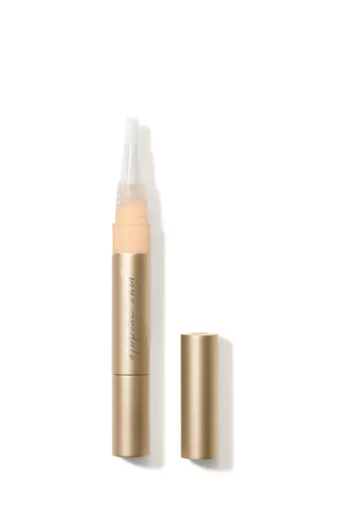 Na zdjęciu znajduje jedna sztuka korektora rozświetlającego Active Light marki Jane Iredale. Produkt ma eleganckie, złote opakowanie w formie pisaka z pędzelkowym aplikatorem. Dostępny jest w różnych odcieniach, dopasowanych do karnacji.
