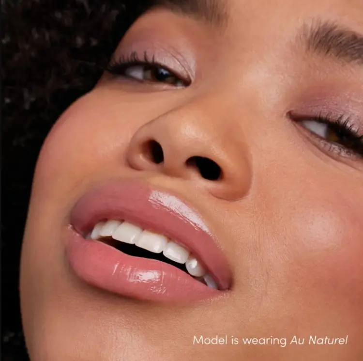 Na obrazku jest modelka z ustami pomalowanymi  odcieniem błyszczyka do ust Jane Iredale o nazwie  Au Naturel. Au Naturel to delikatny, ciepły odcień nude z nutą różu.  Daje naturalny, subtelny efekt z połyskiem – idealny na co dzień.