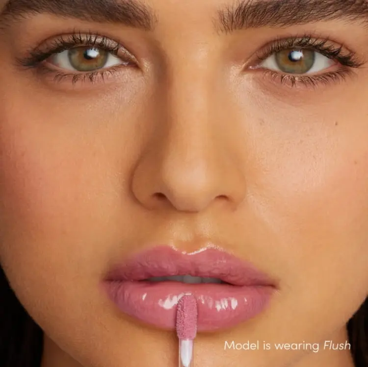 Na obrazku jest modelka z ustami pomalowanymi  odcieniem błyszczyka do ust Jane Iredale o nazwie Flush.  Flush to chłodny, różany odcień z delikatnym połyskiem. Ten odcień świetnie pasuje do makijażu w chłodnych tonacjach i rozświetlonej cery.