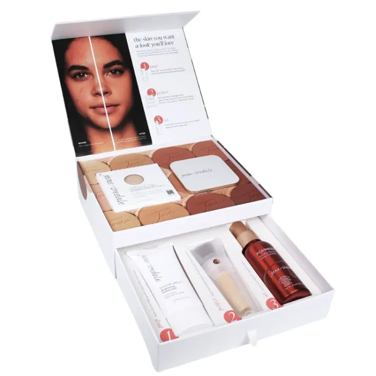 Na zdjęciu widać zestaw kosmetyków marki jane iredale, w tym palety i podkłady mineralne, puder w kompakcie, pędzel, tubkę preparatu Smooth Affair oraz czerwoną mgiełkę Pommisst, ustawione obok ozdobnego opakowania z hasłem „makeup made for skin”.