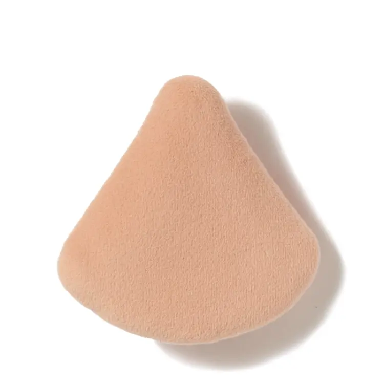 Na zdjęciu jest gąbka do makijażu marki jane iredale,  służąca do nakładania podkładu. Beżowy materiał,  trójkątny kształt – idealny do precyzyjnej aplikacji w okolicach oczu i nosa.