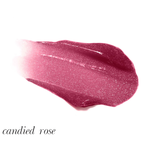 Na zdjęciu znajduje się błyszczyk do ust marki Jane Iredale w odcieniu Candied Rose. Kolor to intensywny róż z nutą śliwki, wzbogacony połyskującymi drobinkami, które nadają ustom efekt mokrego blasku i głębi.