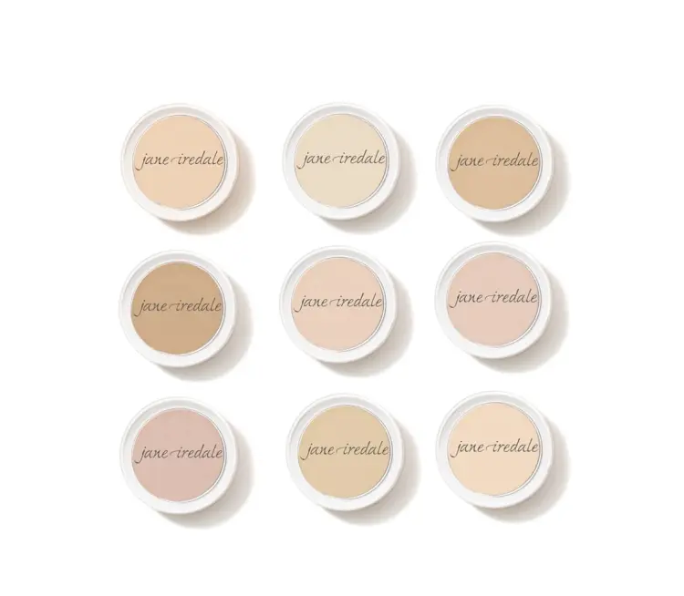 Na zdjęciu widać dziewięć okrągłych pudrów w wersji mini marki Jane Iredale, ułożonych w siatkę 3x3. Każdy z nich ma inny odcień – od bardzo jasnych po nieco ciemniejsze tonacje, idealne do dopasowania do różnych typów cery.
