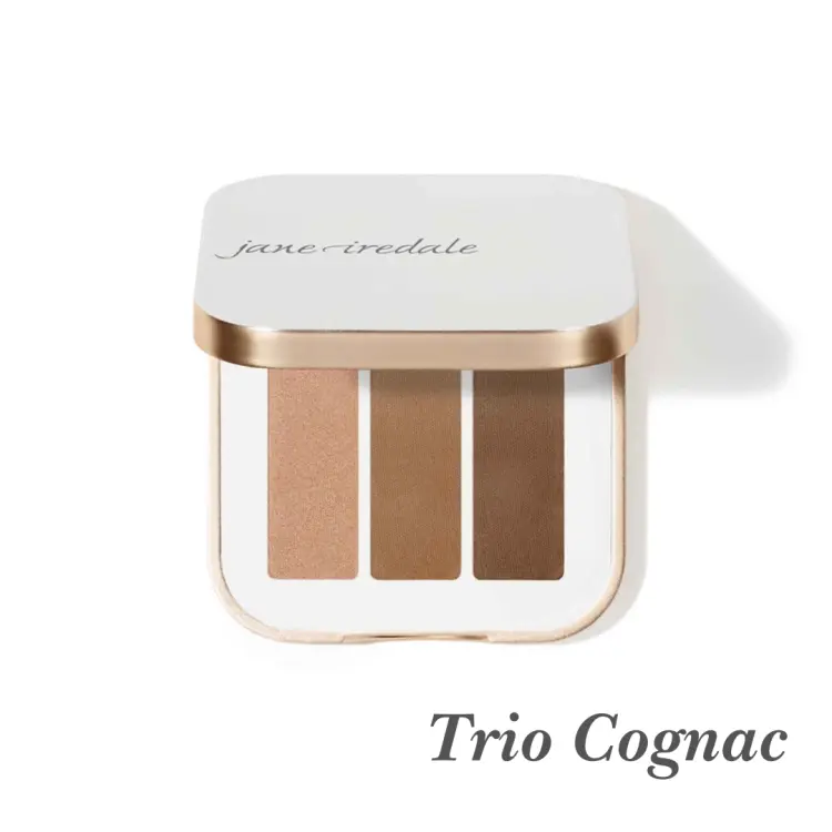 Na zdjęciu jest potrójna paletka cieni do powiek Jane Iredale w odcieniu Trio Cognac. Zestaw zawiera trzy odcienie w ciepłej, brązowej tonacji: połyskujący miedziany brąz, matowy karmelowy brąz, matowy kasztanowy brąz.