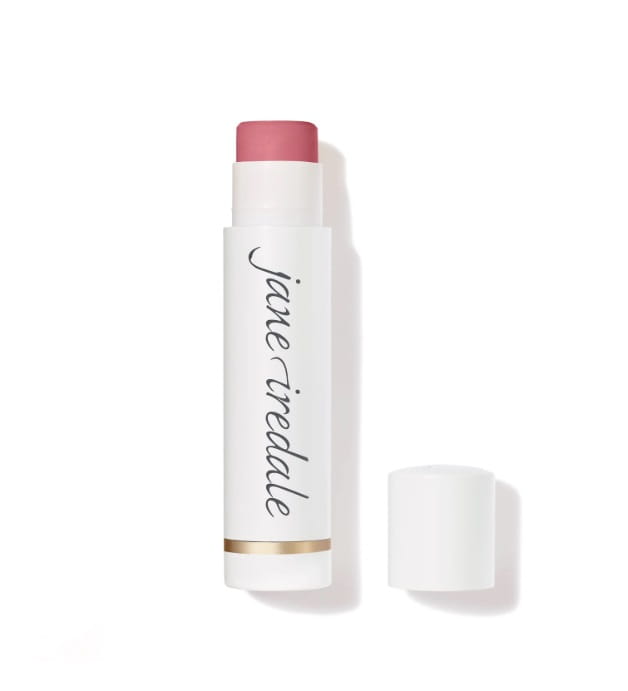 Na zdjęciu znajduje się balsam do ust marki jane iredale Lip Drink. Produkt ma eleganckie, białe opakowania z logo marki i złotym akcentem przy podstawie.