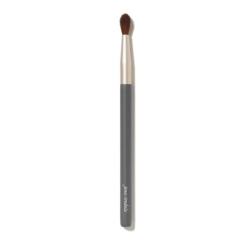 Na zdjęciu znajduje się pędzelek do oczu marki Jane Iredale. Ma elegancki, smukły trzonek w kolorze grafitu z napisem,  ściętą końcówkę z ciemnego włosia.  Pędzel jest przeznaczony do precyzyjnego nakładania cieni.