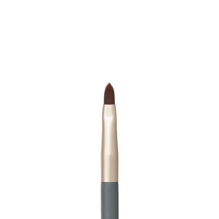 Na zdjęciu jest zbliżenie na pędzelek do ust z kolekcji jane iredale. Ma precyzyjny, spiczasty kształt włosia, który umożliwia dokładne obrysowanie konturu ust i równomierne wypełnienie ich kolorem.