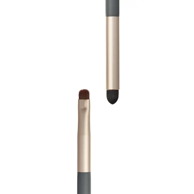 Zdjęcie przedstawia zbliżenie dwóch końcówek dwustronnego pędzelka jane iredale Smudge na białym tle. Po lewej widoczny jest mały, zaokrąglony pędzelek z gęstym brązowym włosiem, a po prawej czarny aplikator gąbkowy.